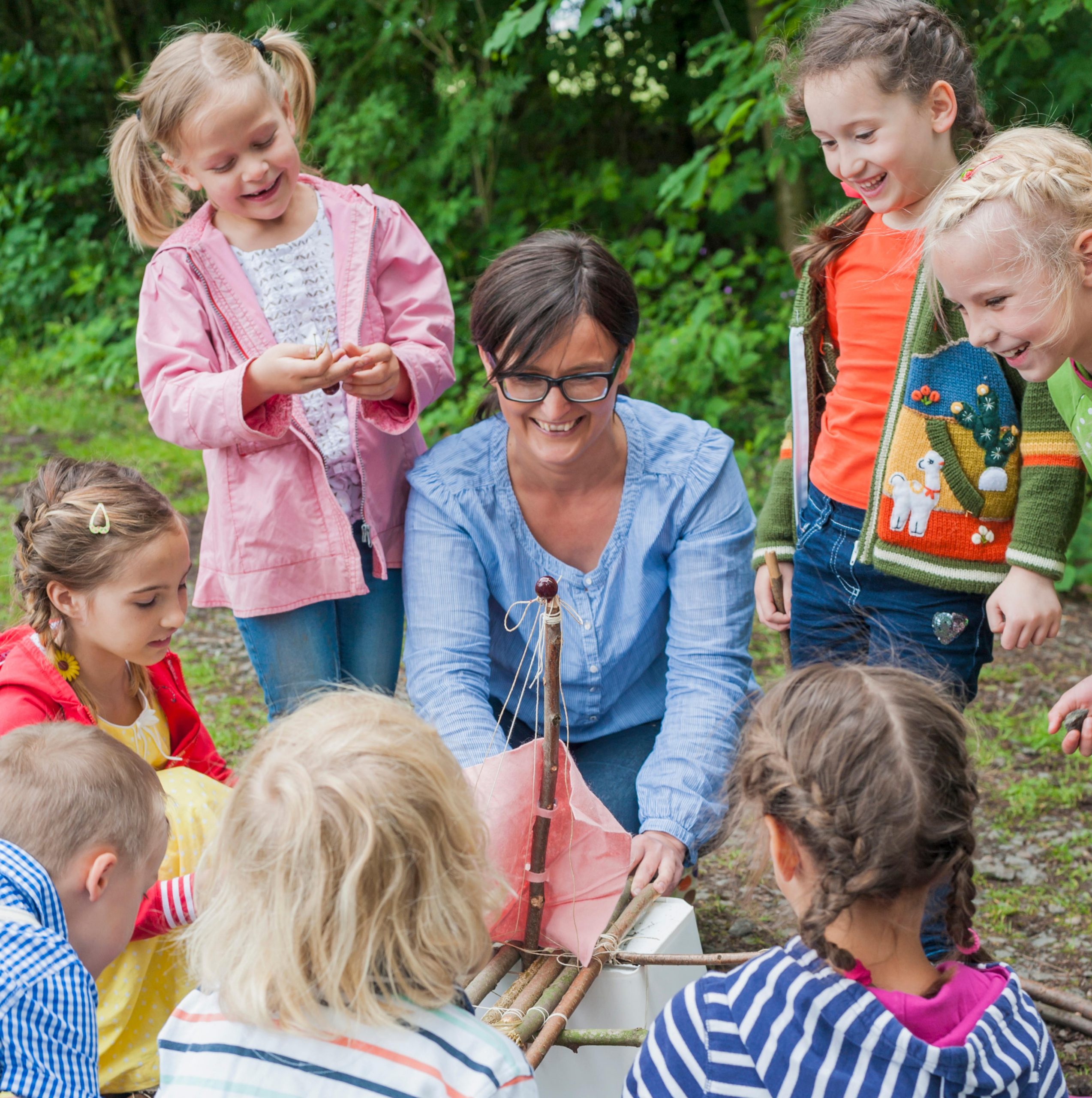 Betreuungsperson zeigt Kindern, wie man ein Boot baut.