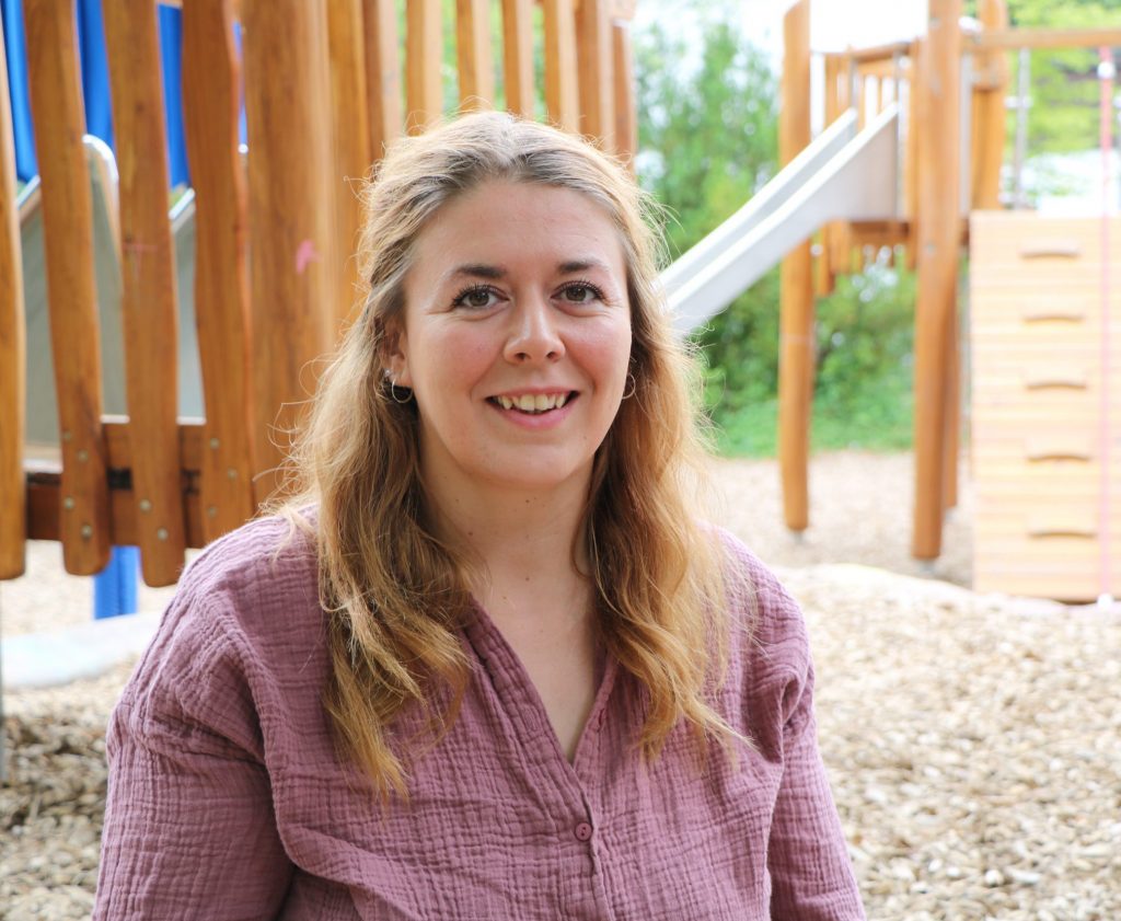 Frau auf Kinderspielplatz, lächelnd.
